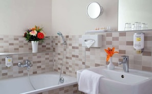 A bathroom with a bathtub, shower, sink, and a mirror. - Agon Spittelmarkt Gmbh (Berlin)