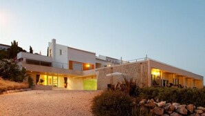 Un edificio moderno con techo plano, amplias ventanas y entrada pavimentada.