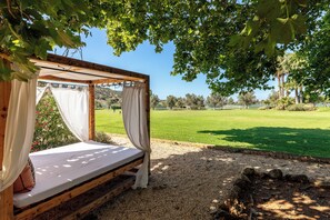 A wooden bed structure with a canopy, set on a gravel surface, overlooking a grassy field. - Vila Valverde Design and Country Hotel (Lagos)