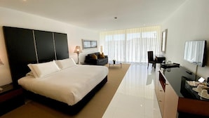 A modern hotel room with a large bed, a desk, a TV, and a seating area with a sofa and armchairs. - Vila Valverde Design and Country Hotel (Lagos)