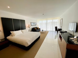 A modern hotel room with a large bed, a desk, a TV, and a seating area with a sofa and armchairs. - Vila Valverde Design and Country Hotel (Lagos)