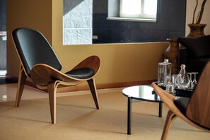 A modern living room with a black leather chair, wooden table, and clear glassware. - Vila Valverde Design and Country Hotel (Lagos)