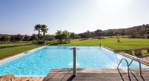 Une piscine dotée d’une terrasse en bois et bordée de pierres.