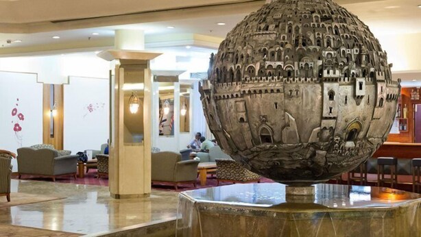 A lobby with a large spherical sculpture, seating areas, and a reception desk. - King Solomon (Jerusalem)