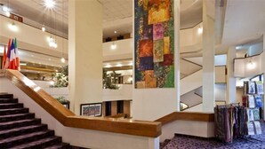 A hotel lobby with a staircase, a large abstract painting, and a display of clothing. - Cassia Hotel Jerusalem (Jerusalem)