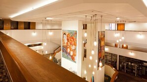 A hotel lobby with a wooden reception desk, a staircase, and a wall with colorful artwork. - King Solomon (Jerusalem)