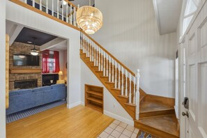 A spacious living area with a wooden staircase, a fireplace, and a blue sofa. - Sleeps 10 • Heated Pool • Game Room • Hot Tub (Largo)