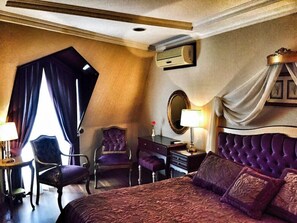 A hotel room with a large bed, a vanity with a mirror, a desk, and two chairs. - Hotel Daphne (Istanbul)