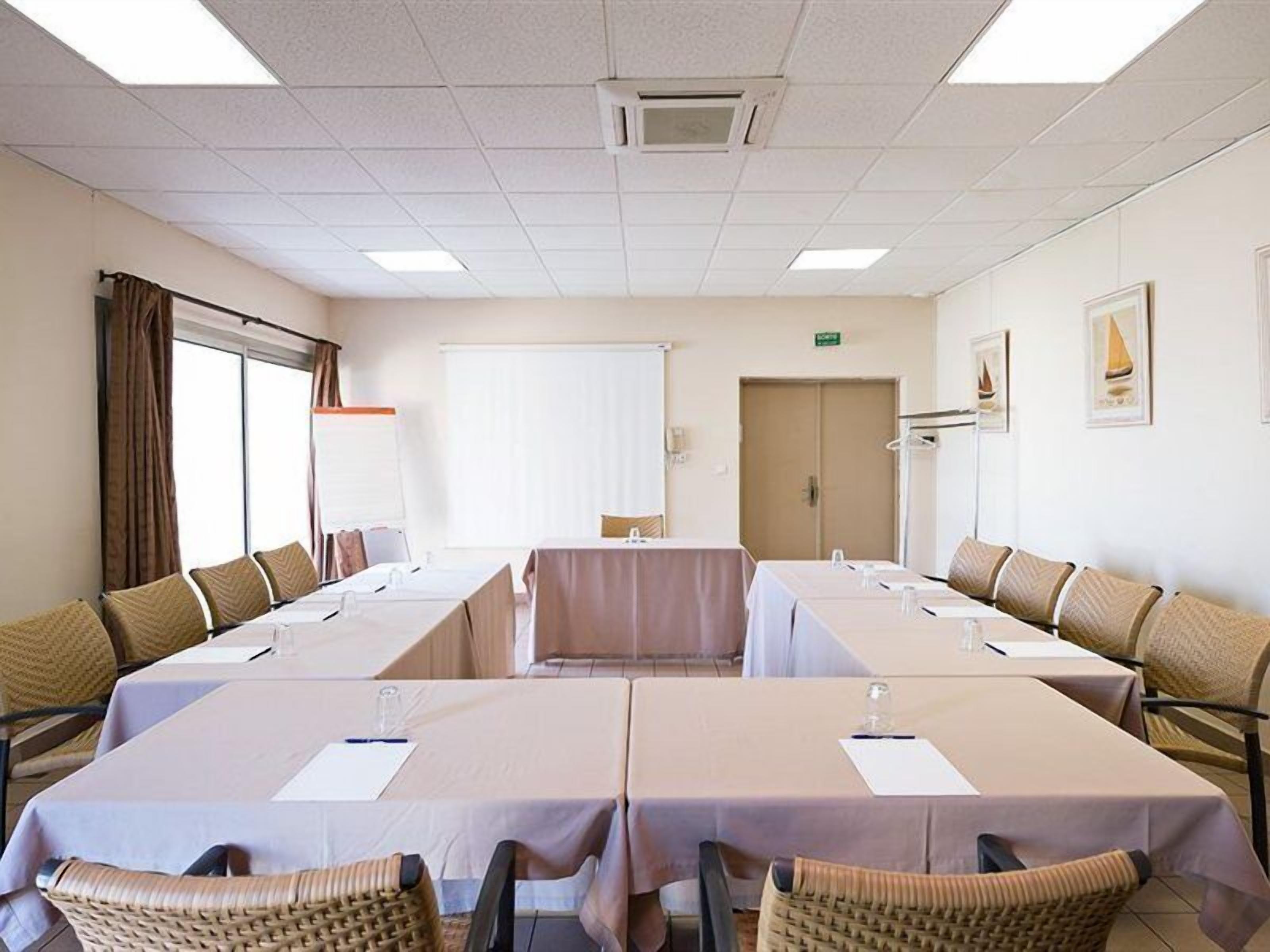 Une salle de conférence avec de longues tables, des chaises et une grande fenêtre.
