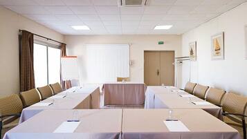 Une salle de conférence avec de longues tables, des chaises et une grande fenêtre.