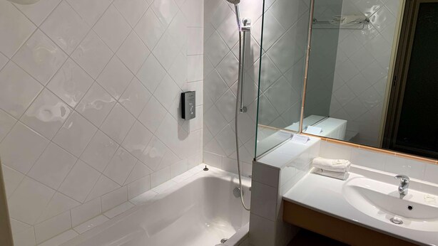 A modern bathroom with a glass-enclosed shower, a white bathtub, and a sink with a mirror above it. - Hotel Paradou (Avignon)
