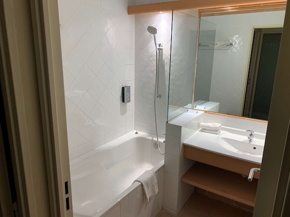 A bathroom with a bathtub, a shower, a sink, and a mirror.
