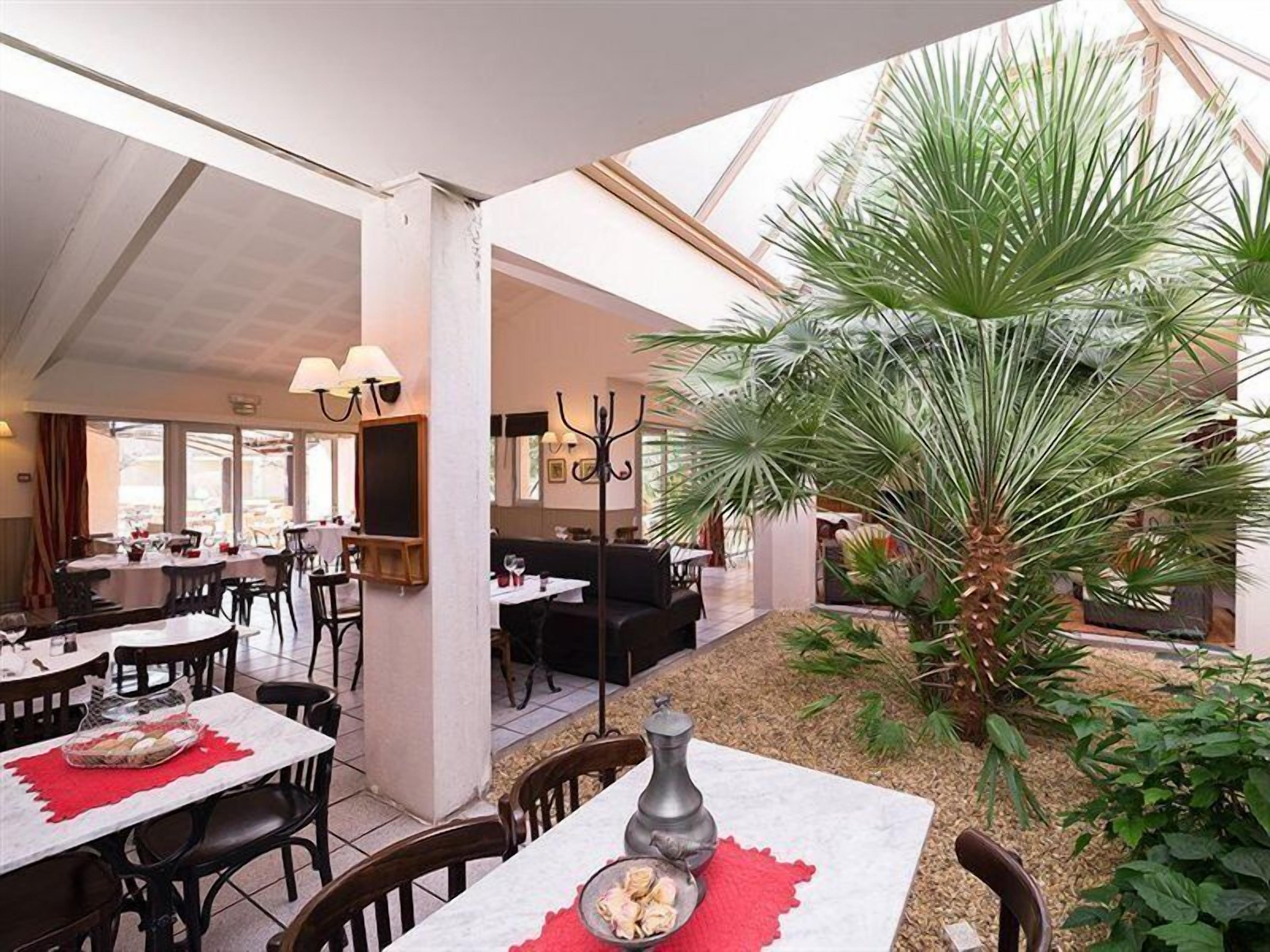 Un restaurant doté d’une salle à manger intérieure, d’une plante centrale et d’un plafond haut.
