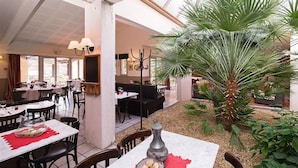 A restaurant with indoor seating, a central plant, and a high ceiling. - Hotel Paradou (Avignon)