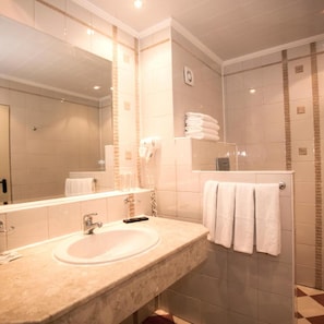 A bathroom with a sink, mirror, towel rack, and shower area. - Hotel Royal Bay (Nessebar)