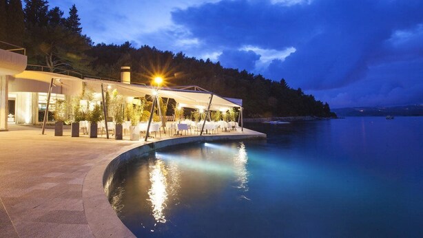 A waterfront property with a pool, outdoor seating, and a building with a modern design. - Croatia Hotel (Konavle)