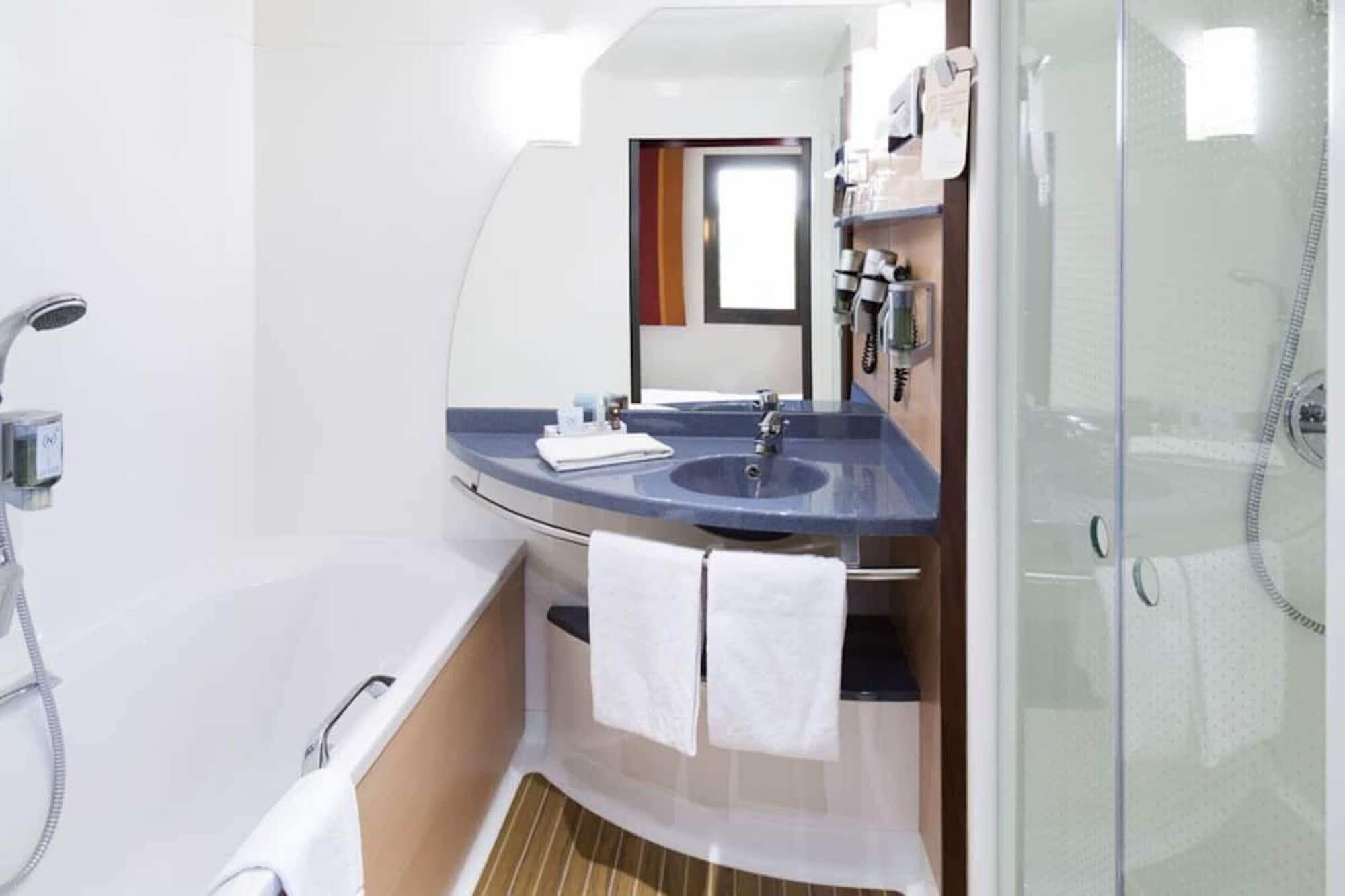 Un baño pequeño con bañera, lavabo, espejo y ducha.