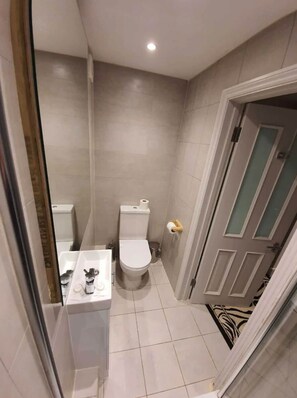 A small bathroom with a toilet, sink, and a door leading to another room. - W6 Hotel (London)