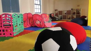 A room with colorful play mats, a black and white soccer ball, and a window with natural light. - Sauipe Pousadas (Mata de São João)