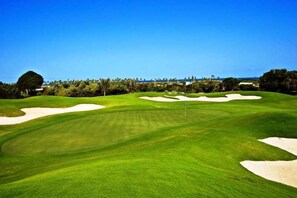 A golf course with sand bunkers, a flagstick, and a clear blue sky. - Sauipe Pousadas (Mata de São João)