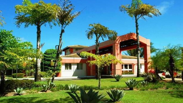 A modern building with a flat roof, surrounded by well-maintained greenery and palm trees. - Sauipe Pousadas (Mata de São João)