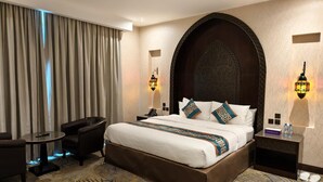 A hotel room with a large bed, a desk, a chair, and two wall-mounted lamps. - Savoy Grande Hotel & Spa (Manama)
