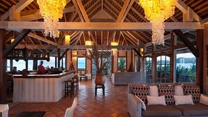 Un amplio salón con barra, asientos y grandes ventanales con vistas panorámicas.