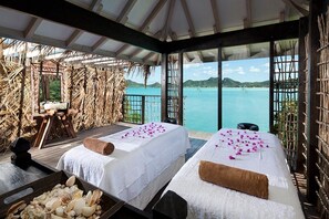 Quarto com duas camas, um deck de madeira, vista para o mar e parede de palha.