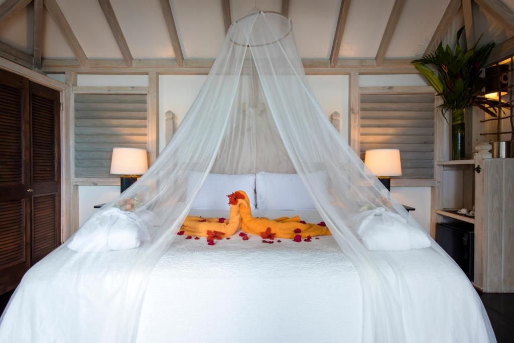 A bed with a canopy, white bedding, and rose petals.