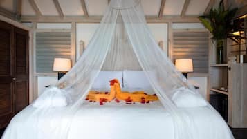 A bed with a canopy, white bedding, and rose petals.