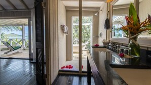 Un baño con ducha, lavabo y vistas a un balcón con una silla.