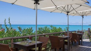 Un restaurante frente al mar con terraza, sombrillas y vistas al océano.