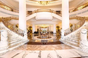 A grand lobby with marble flooring, a central fountain, and a staircase with ornate railings. - Al Habtoor Palace (Dubai)