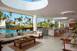 A modern hotel lobby with a pool view, seating areas, and a bar. - Secrets Royal Beach Punta Cana - Adults Only (Punta Cana)