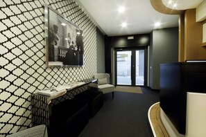 En modern entréhall med en vägg med ett mönster, en receptionsdisk, en sittgrupp och en stor tavla inramad.