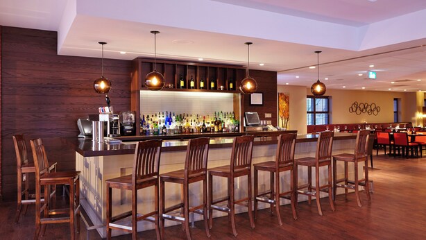 Un área de bar con sillas de madera, una barra y una variedad de botellas.