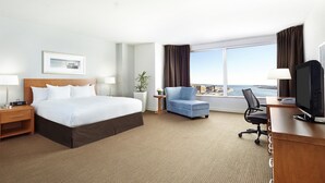 Habitación de hotel con una cama grande, escritorio, silla, televisor y vista al mar.