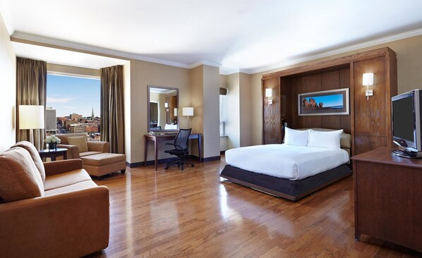 A hotel room with a bed, desk, chair, and a television.