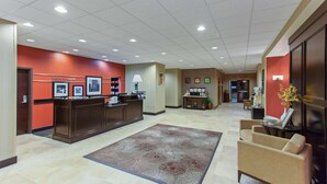 Un hall d’hôtel comprenant un comptoir d’accueil, un espace salon et une grande moquette.