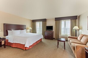 Ein Hotelzimmer mit Bett, Fernseher, Schreibtisch, Stuhl und einer Couch.