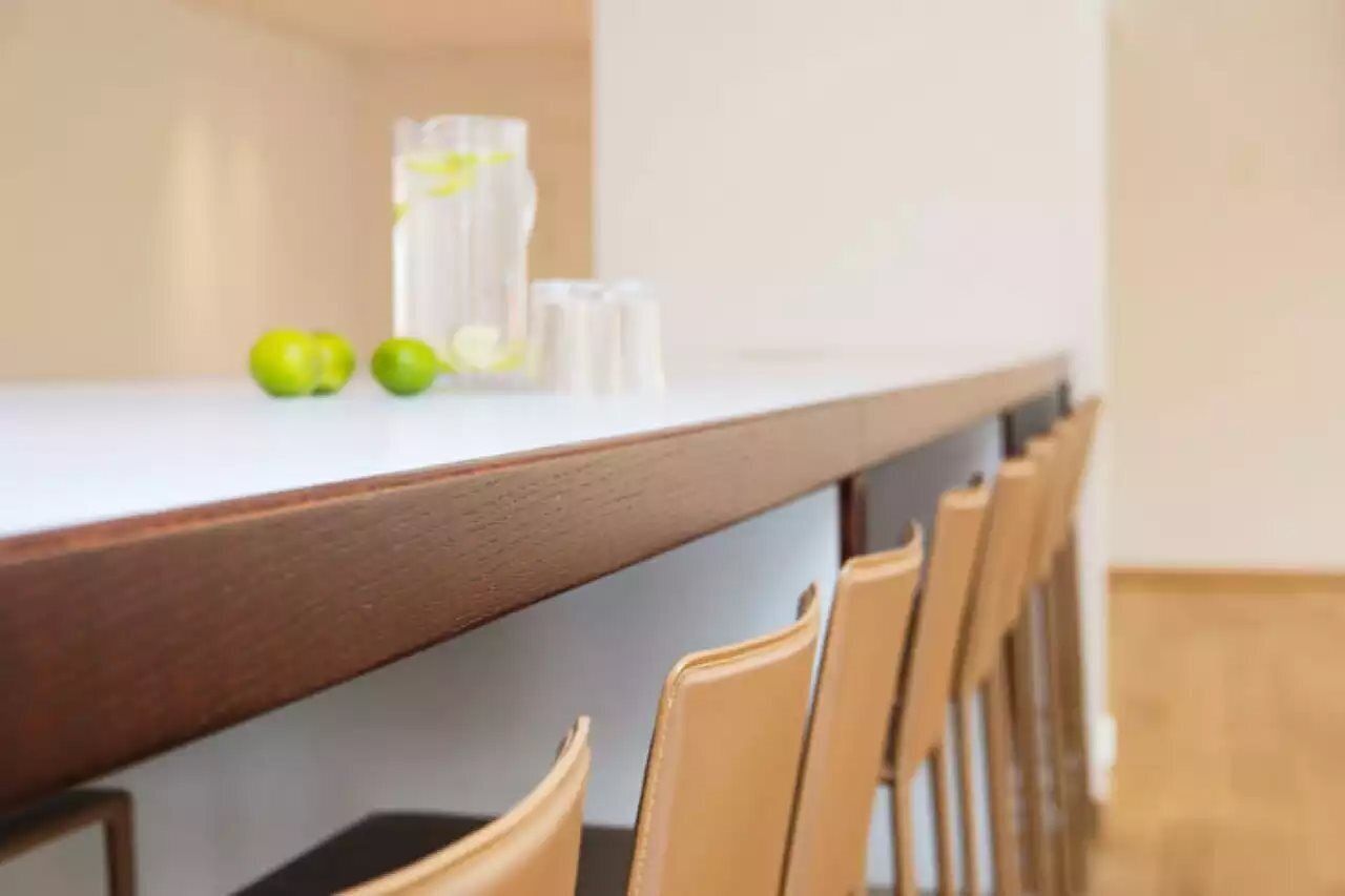 Un coin repas avec une longue table, des chaises, ainsi que quelques pommes et des verres posés sur la table.