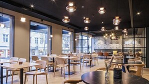 Ein modernes Café mit runden Tischen und Stühlen, großen Fenstern und Pendelleuchten.