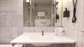 A bathroom with a white sink, a mirror, a towel rack, and a handheld showerhead.