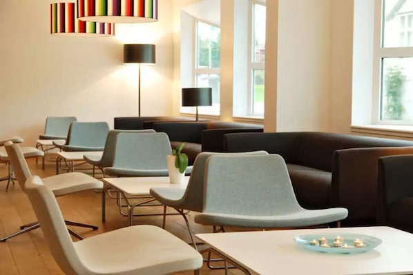 A modern room with seating arrangements, a lamp, and a window.