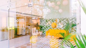 Un hall de hotel con entrada de vidrio, un sofá amarillo y una pared con estampado.