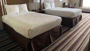 A hotel room with two beds, a nightstand, a lamp, a chair, and a window with curtains. - Best Western Windsor Inn & Suites (Danville)