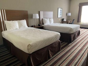 A hotel room with two beds, a nightstand, a lamp, a chair, and a window with curtains. - Best Western Windsor Inn & Suites (Danville)