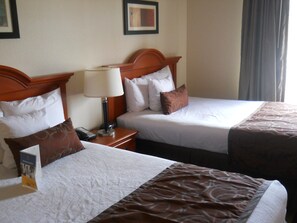 Two adjacent hotel beds with headboards, a bedside table with a lamp, and a framed picture on the wall. - Best Western Windsor Inn & Suites (Danville)