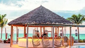 A poolside bar area with a thatched roof, lounge chairs, and a pool. - Hilton At Resorts World Bimini (Alice Town)