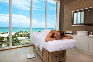 A room with a large window, a bed, a wooden cabinet, and a mirror.